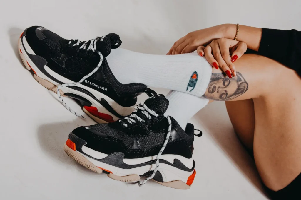 Photograph of women legs wearing white socks and Balenciaga brand trainers